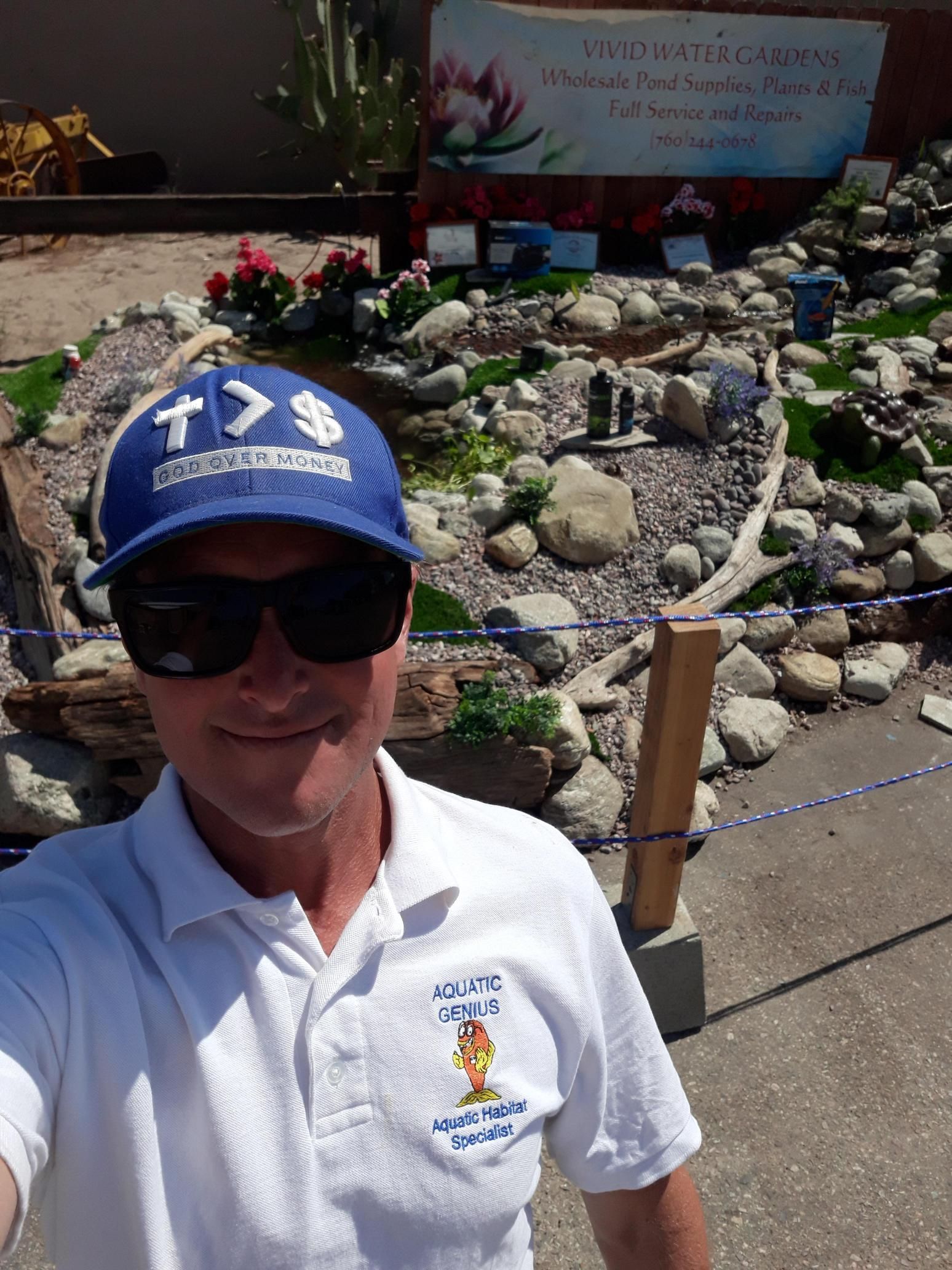 A man wearing a blue hat and sunglasses is taking a selfie