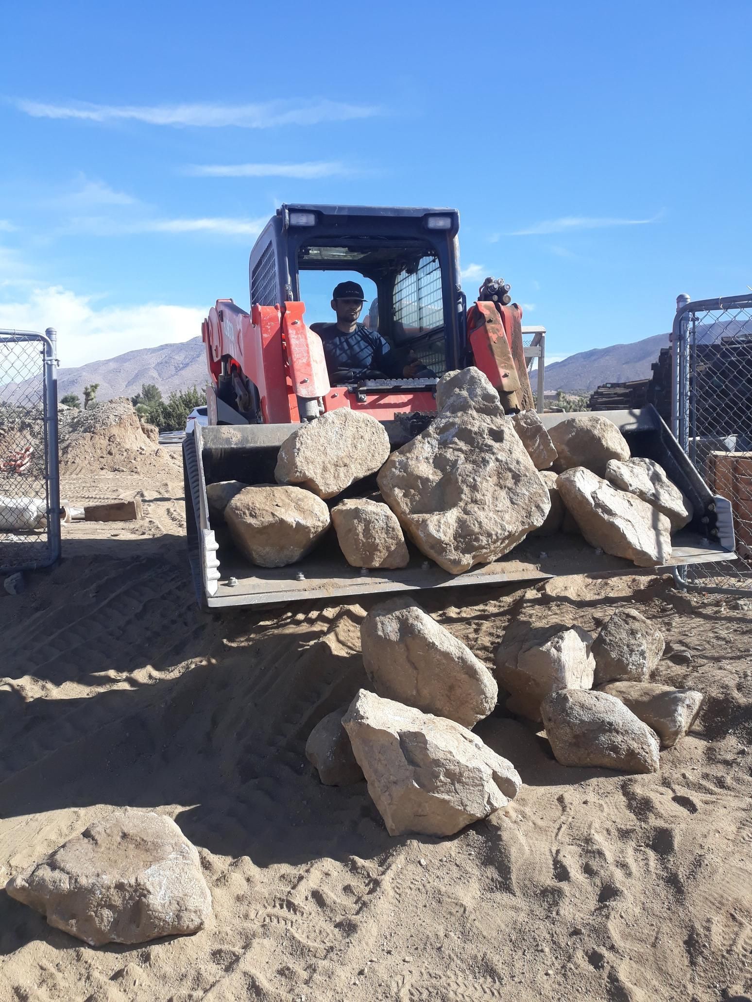A bulldozer is carrying a pile of rocks in the dirt