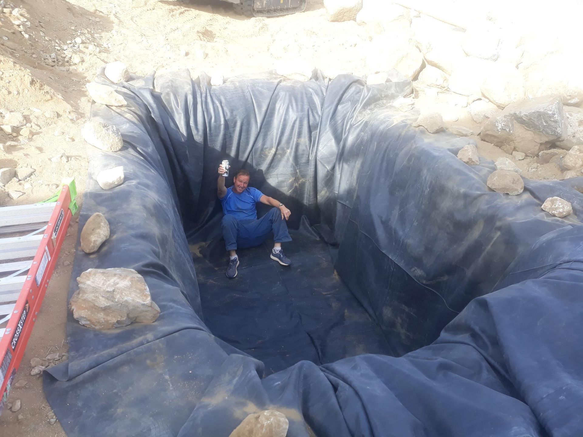 A man is sitting in a large hole in the ground.