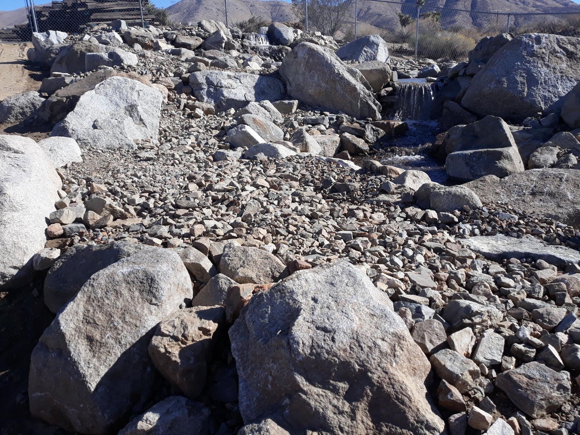 A pile of rocks in the desert with mountains in the background