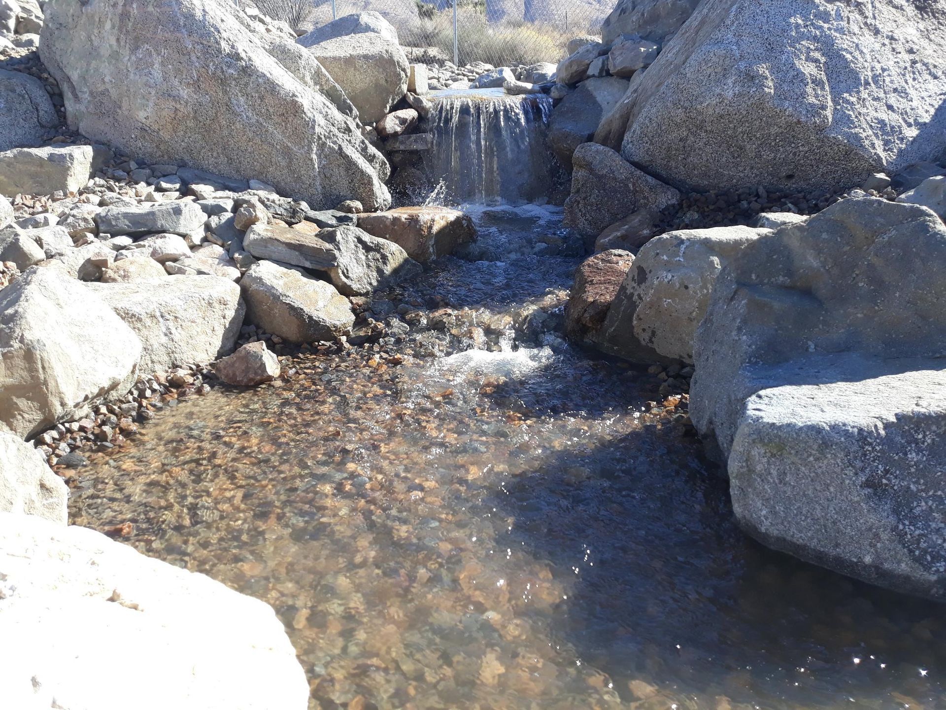 A small waterfall is surrounded by rocks and water
