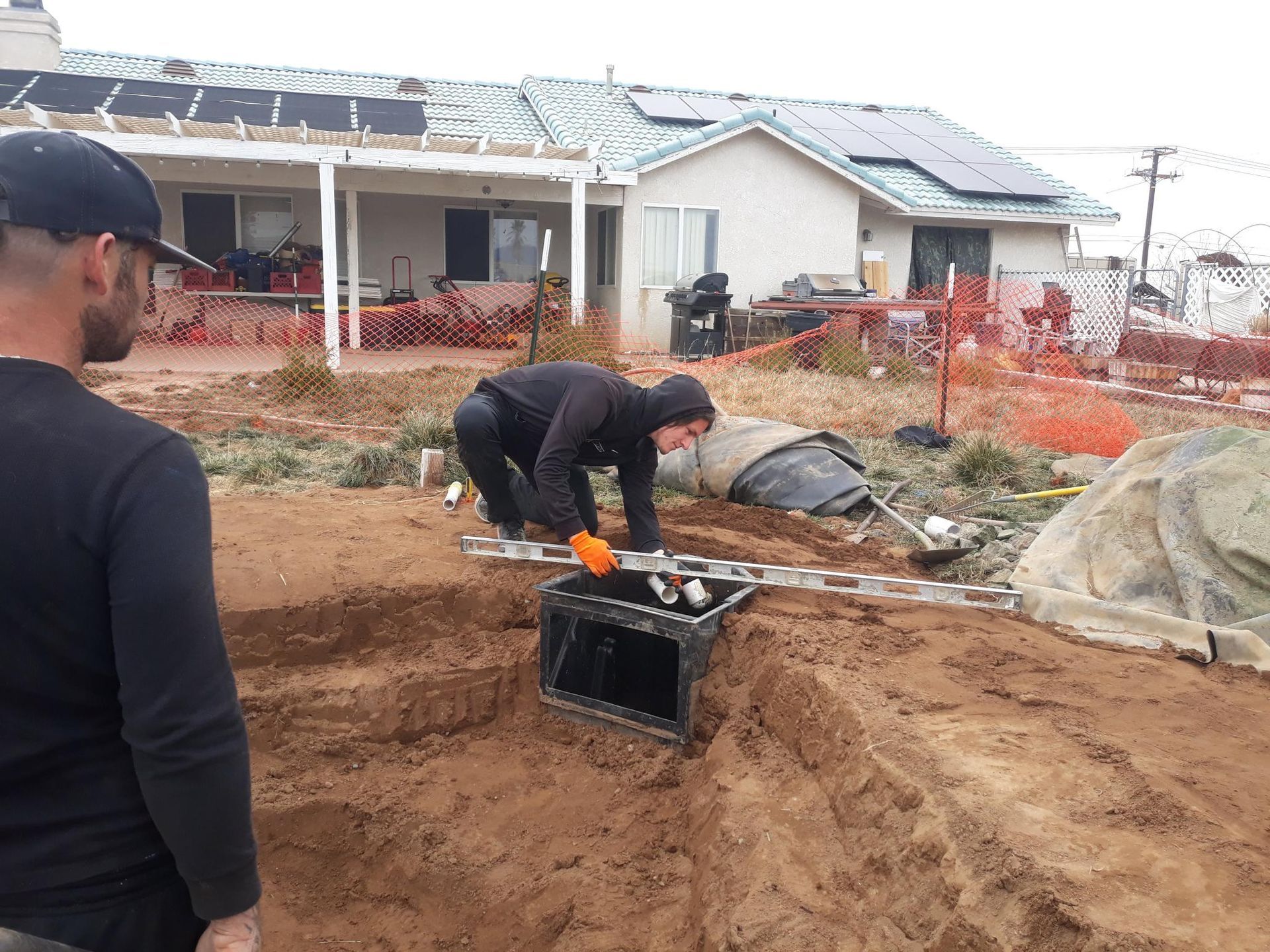 Two men are working in the dirt in front of a house.