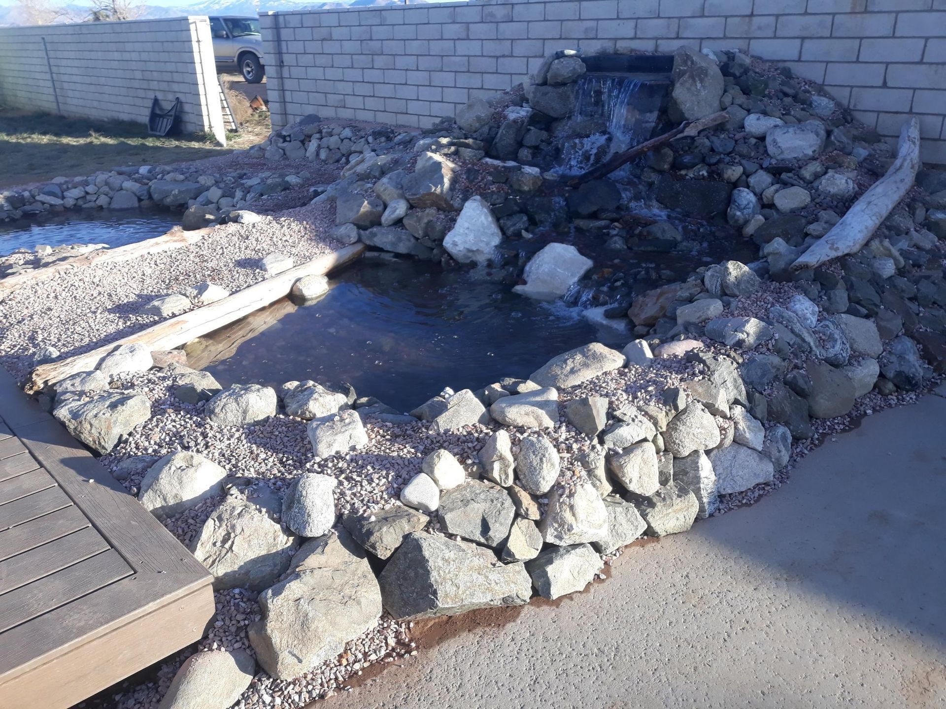 A pond surrounded by rocks and a brick wall