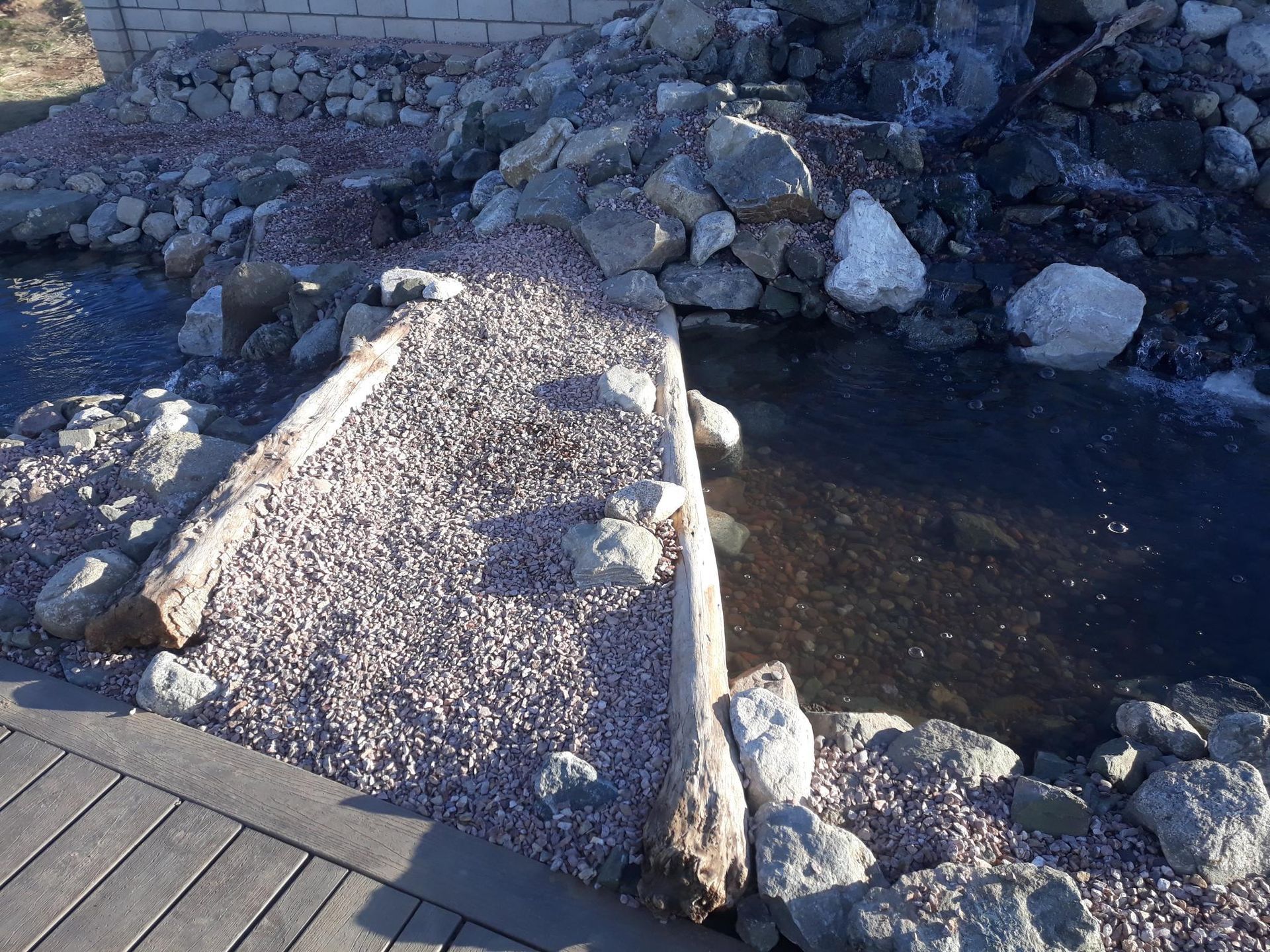 A wooden bridge over a river surrounded by rocks and gravel
