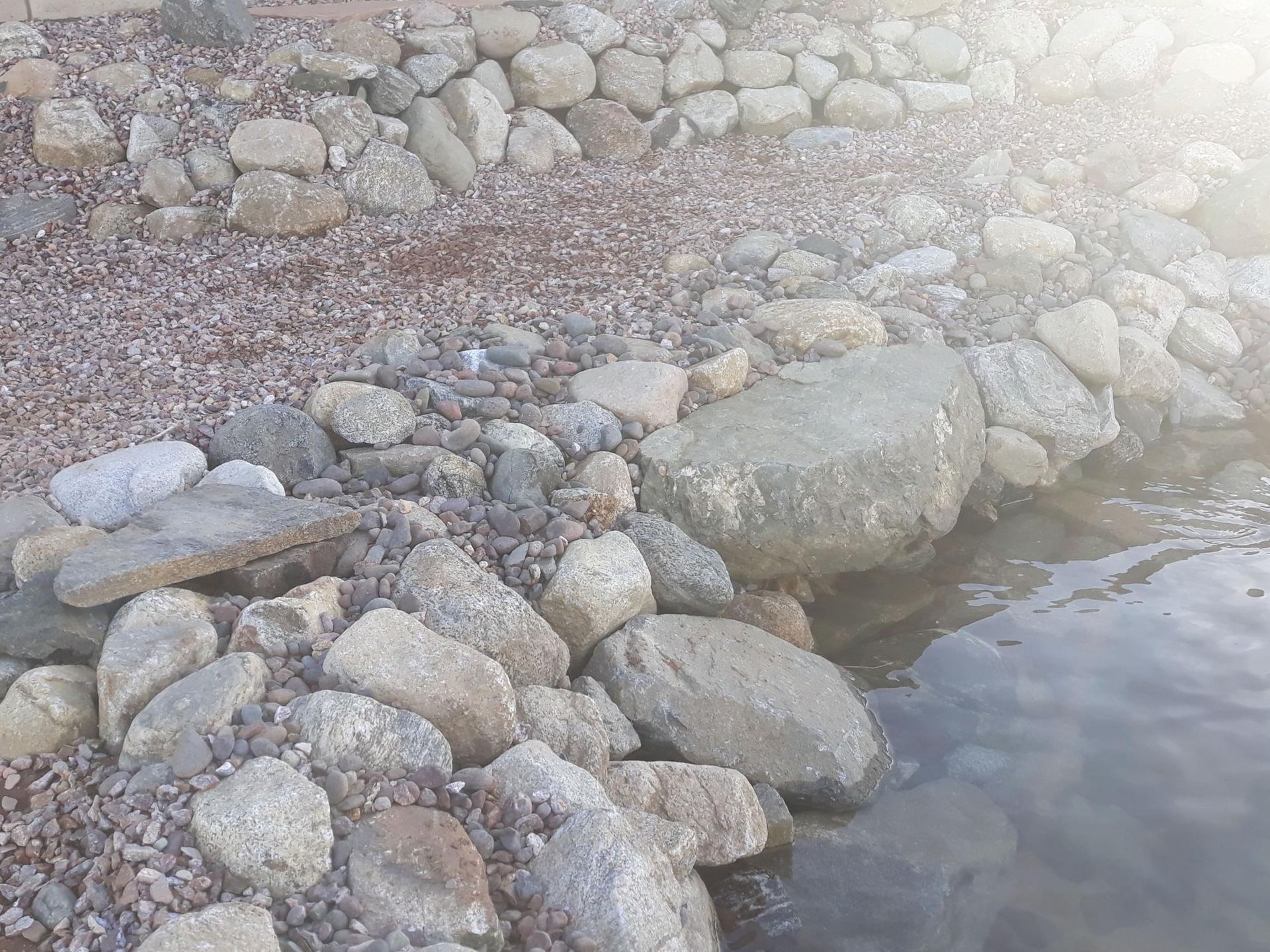 A pile of rocks next to a body of water.