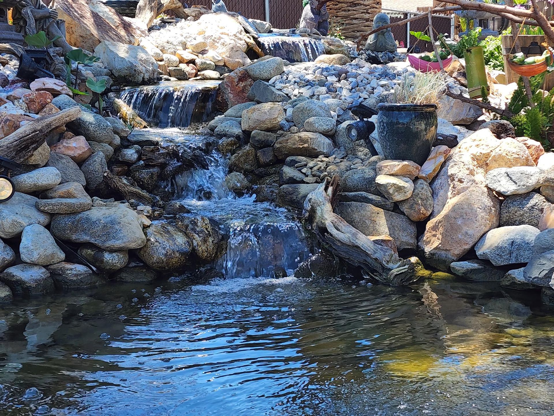 There is a waterfall in the middle of a pond surrounded by rocks.