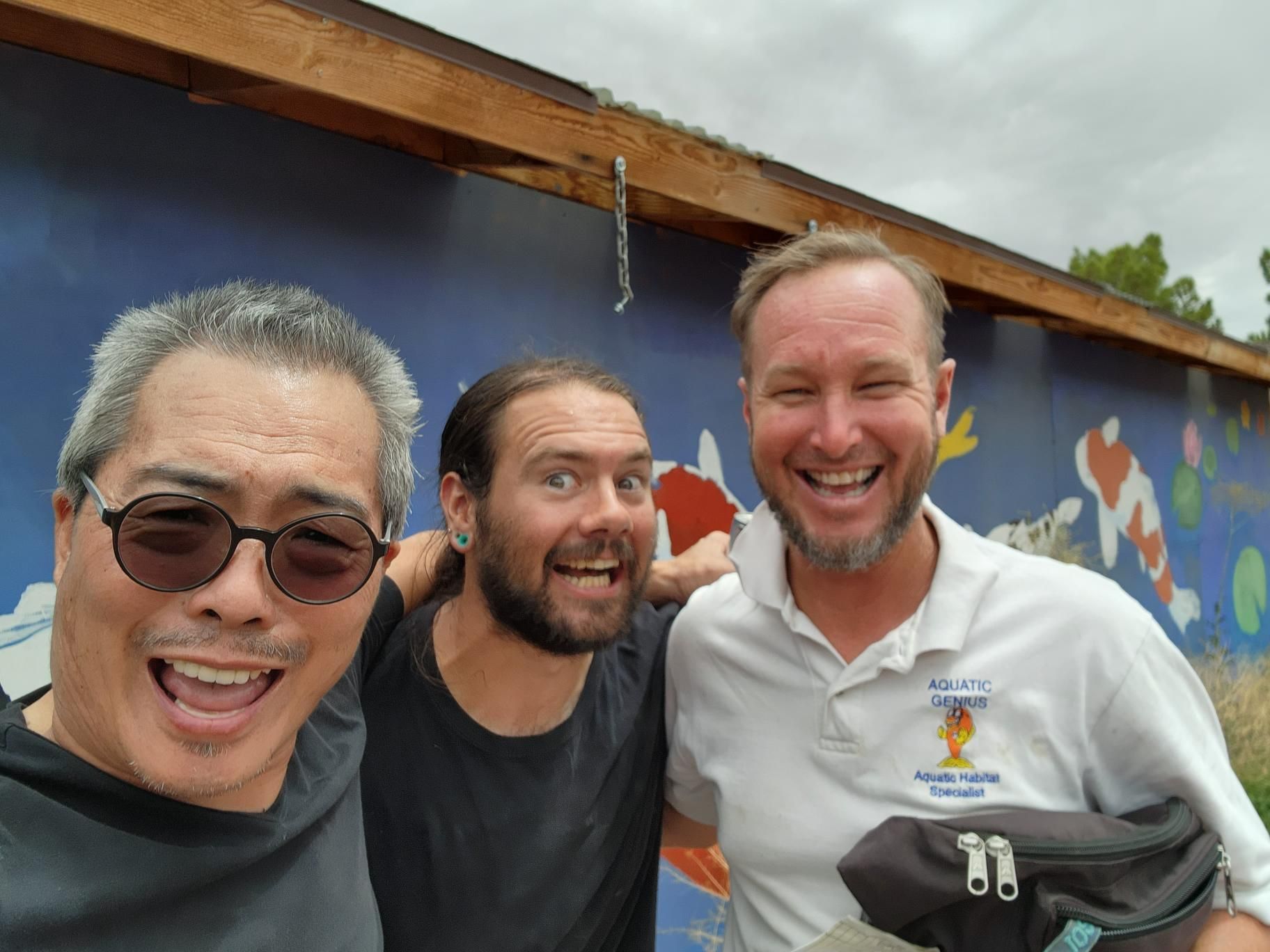 Three men are posing for a picture in front of a colorful wall.