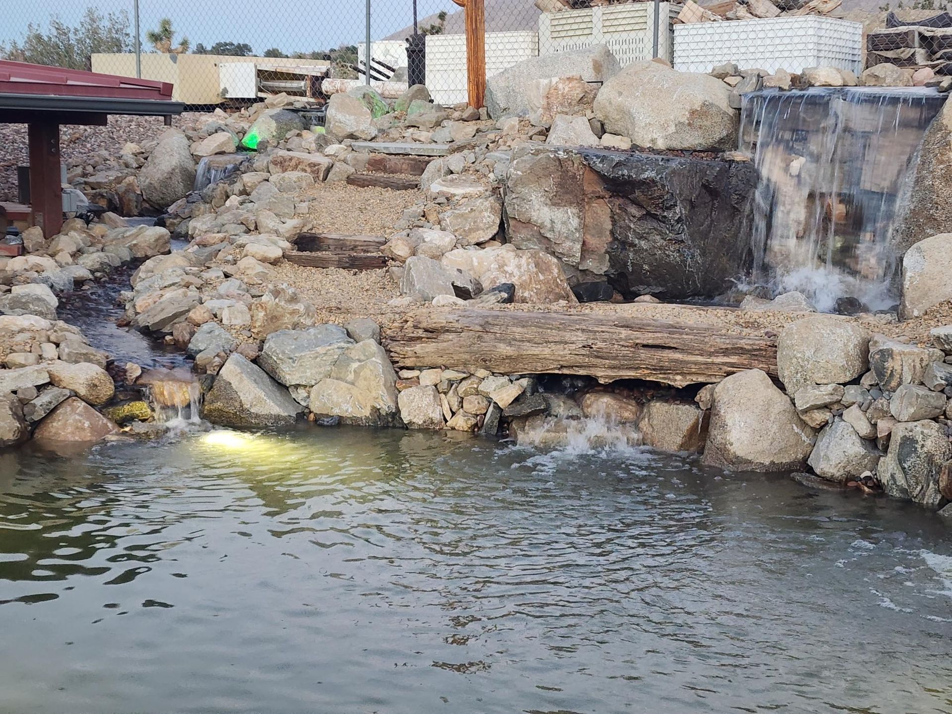 A waterfall is surrounded by rocks and a pond