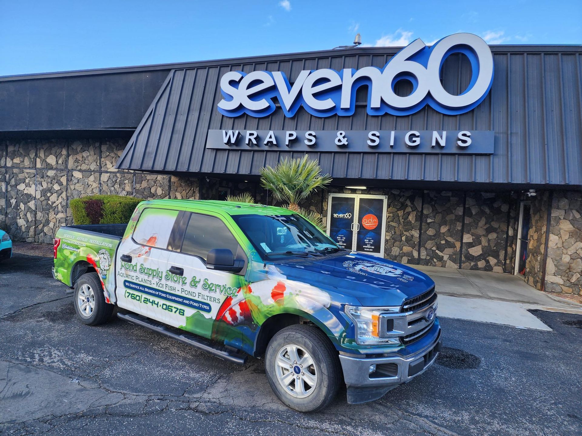 A truck is parked in front of a building that says seven 60 wraps and signs.