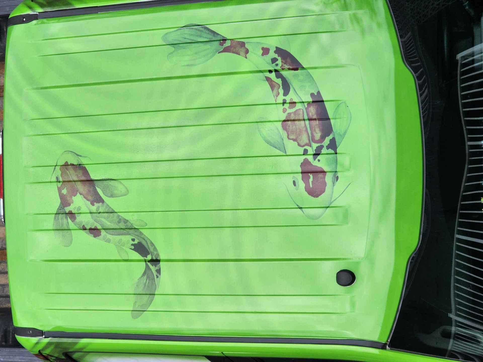 A green car with two fish painted on the roof