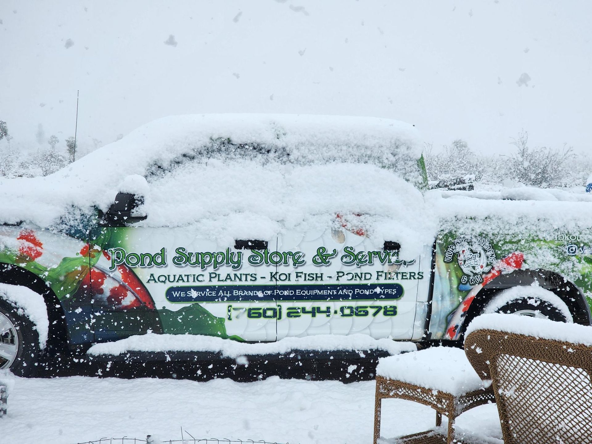 A truck that says pond supply store and service is covered in snow