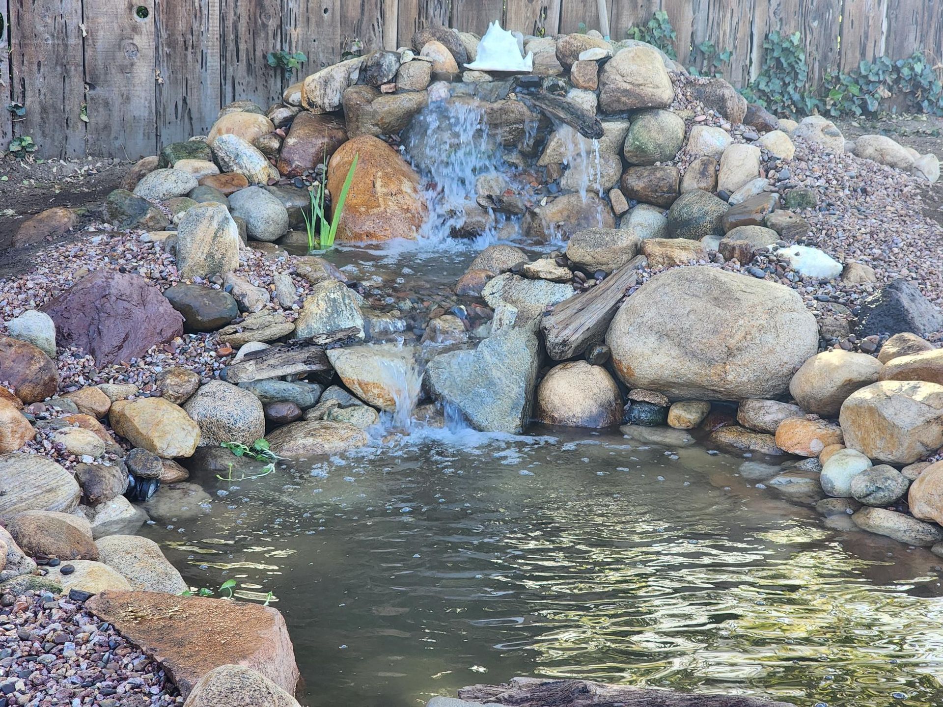 There is a waterfall in the middle of a pond surrounded by rocks.