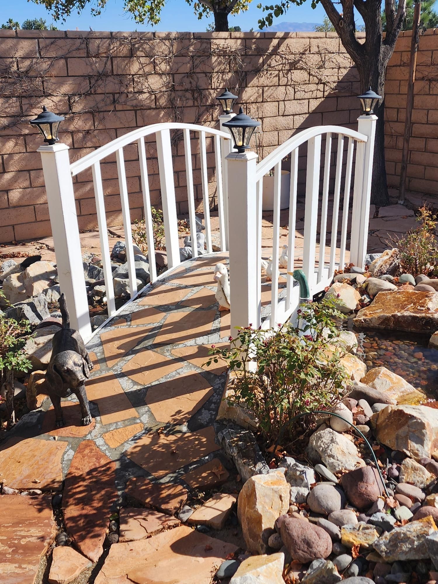 A white bridge over a rocky stream in a garden