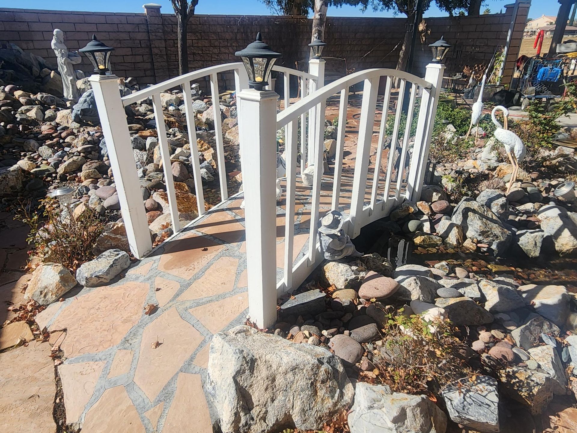 A small white bridge surrounded by rocks in a garden