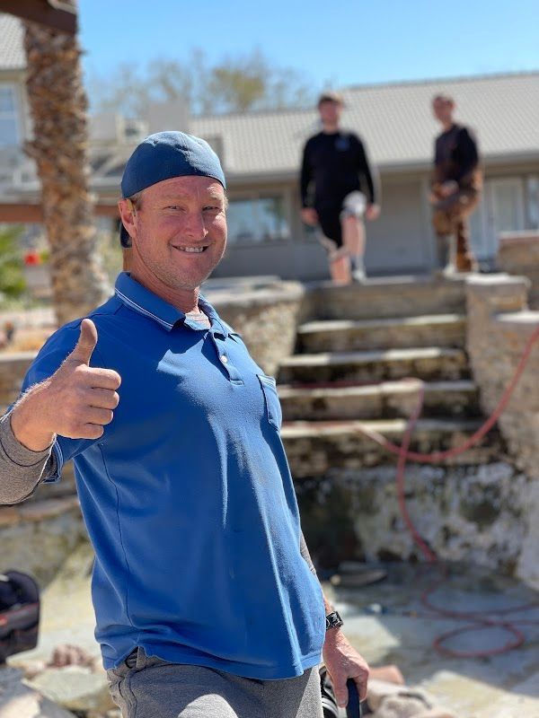 A man in a blue shirt is giving a thumbs up.