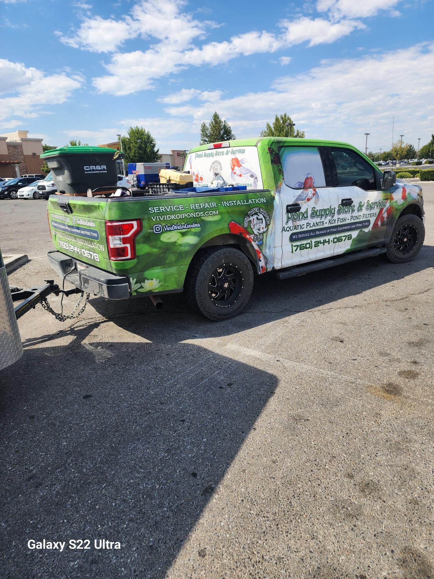 A green and white truck is parked in a parking lot.