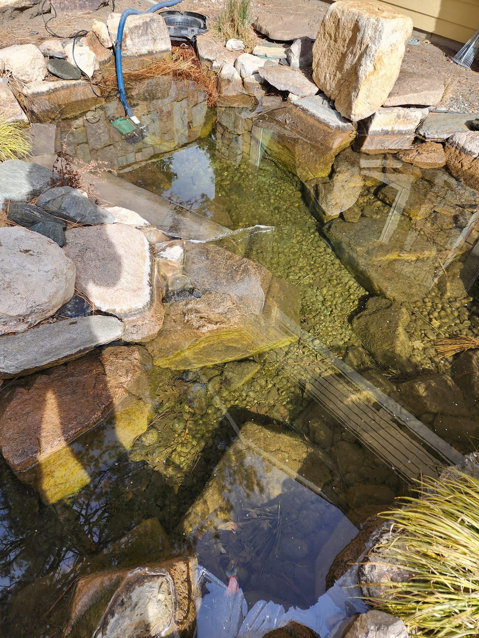 A pond filled with rocks and water with a hose in it.