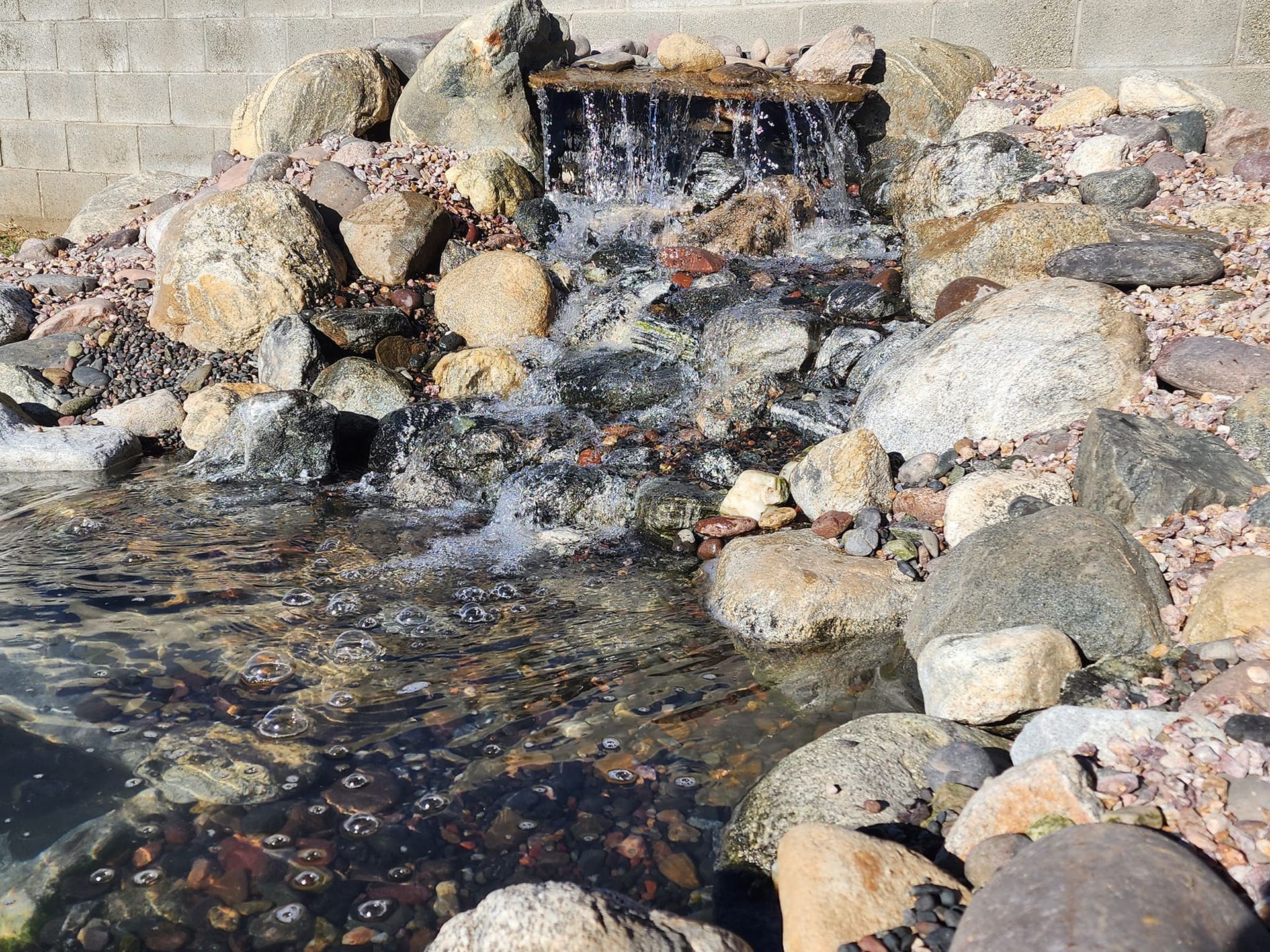 A small waterfall is surrounded by rocks and water.