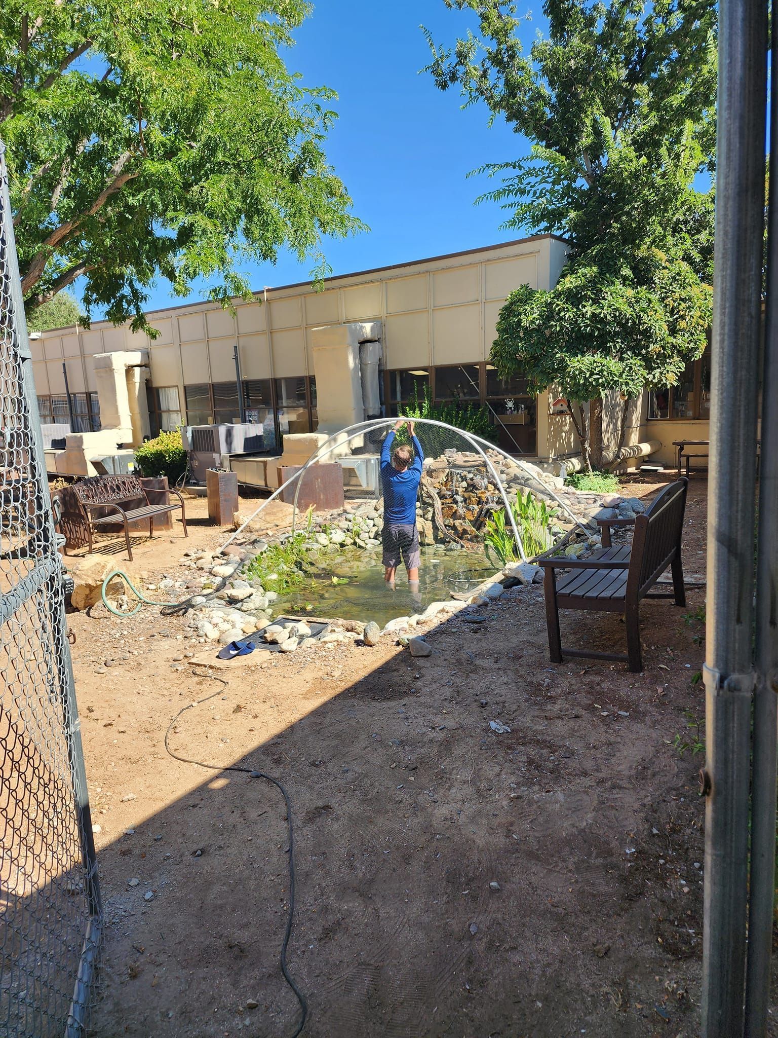 A man is standing in a pond in front of a building.