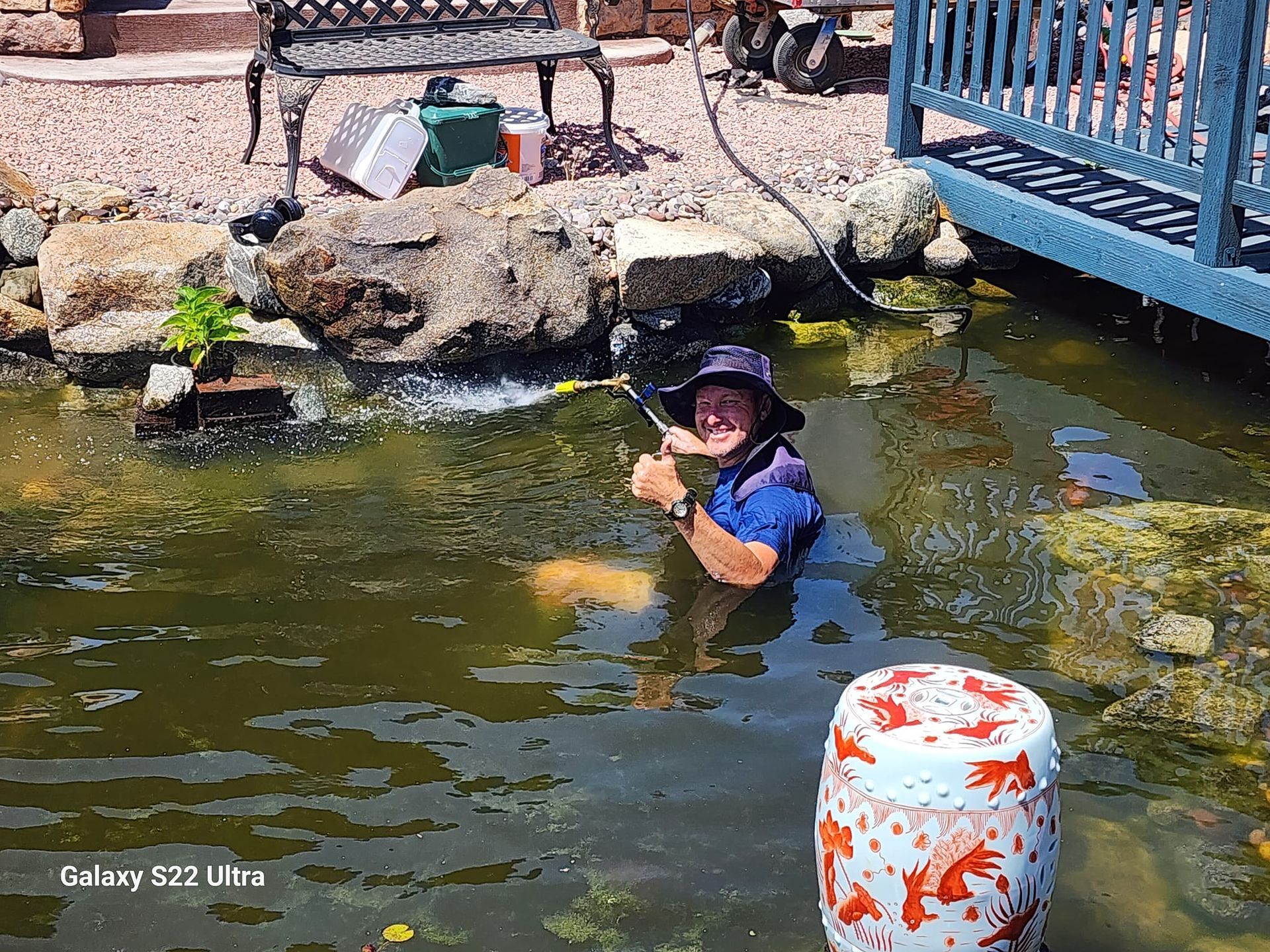 A man is standing in a pond holding a fishing rod.