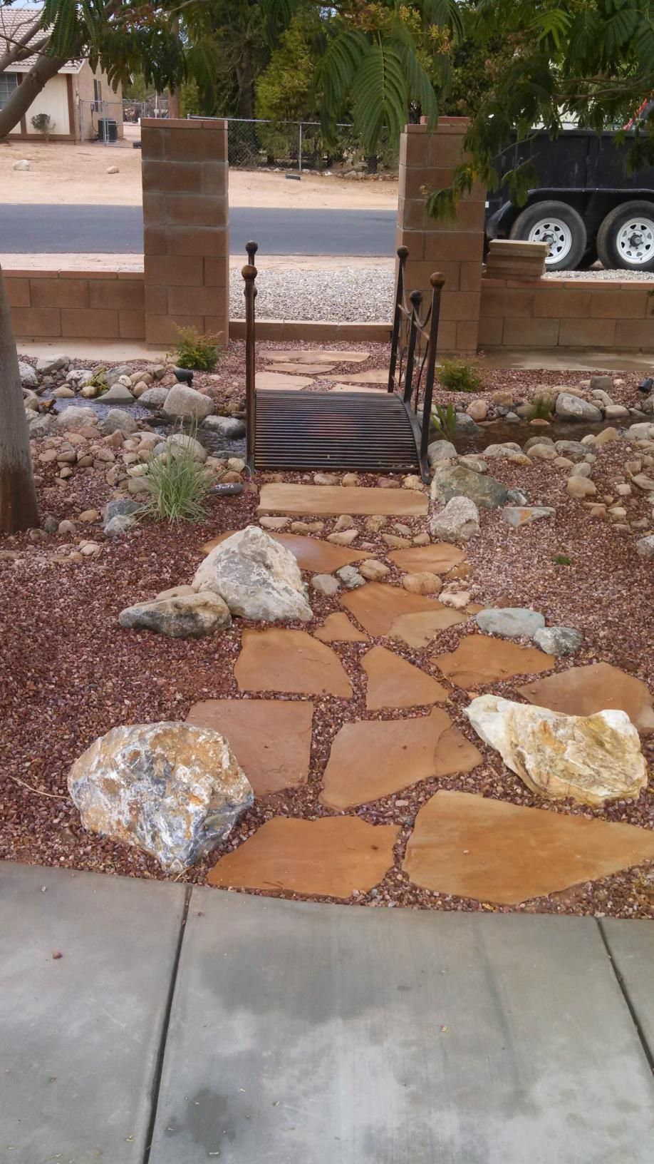 A stone walkway leading to a bridge in a yard.
