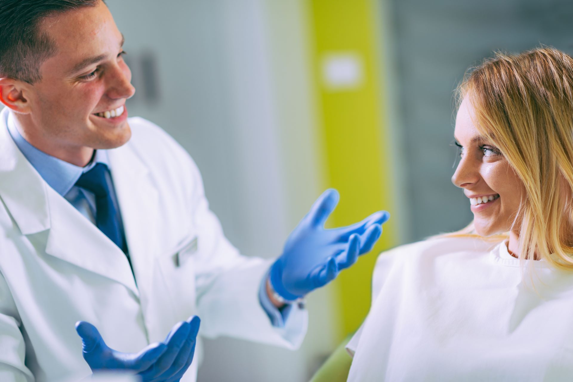 A dentist is talking to a patient in a dental chair.