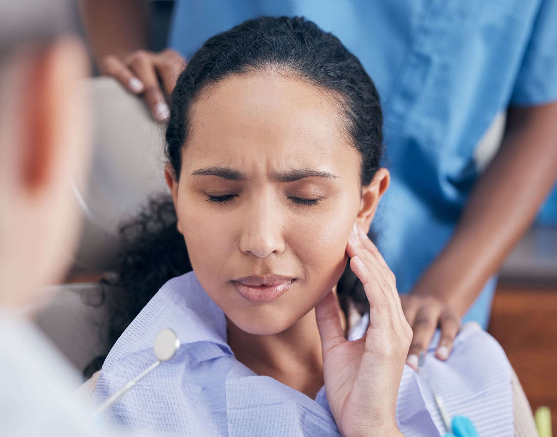 A woman is sitting in a dental chair with a toothache.