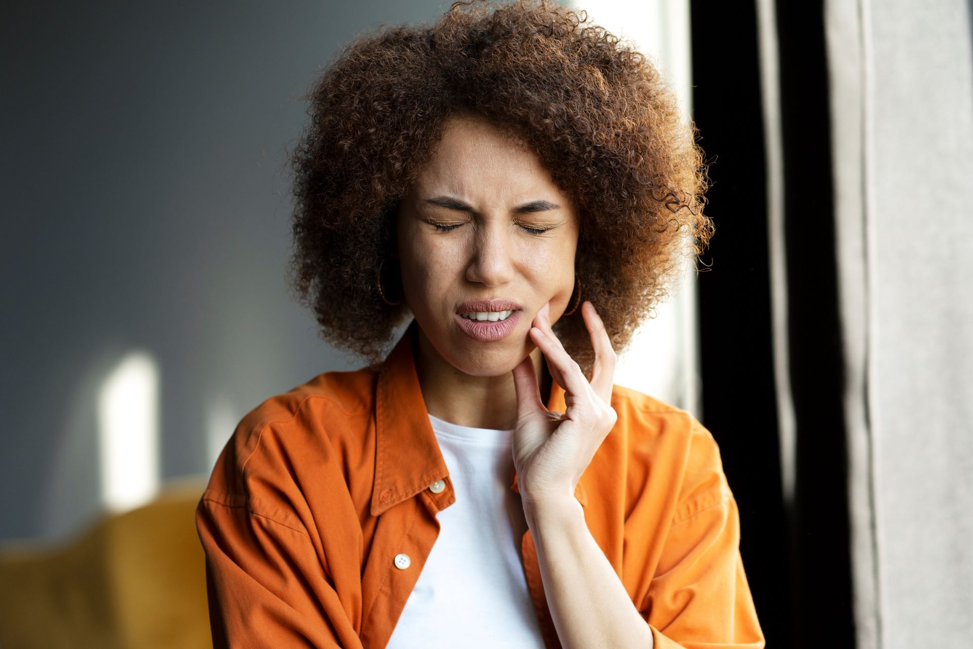 A woman is holding her face in pain because of a toothache.