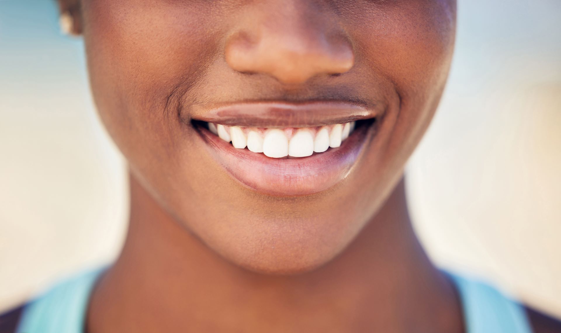 A close-up shot focusing on a bright, friendly smile, showing straight white teeth against a soft, blurred background.