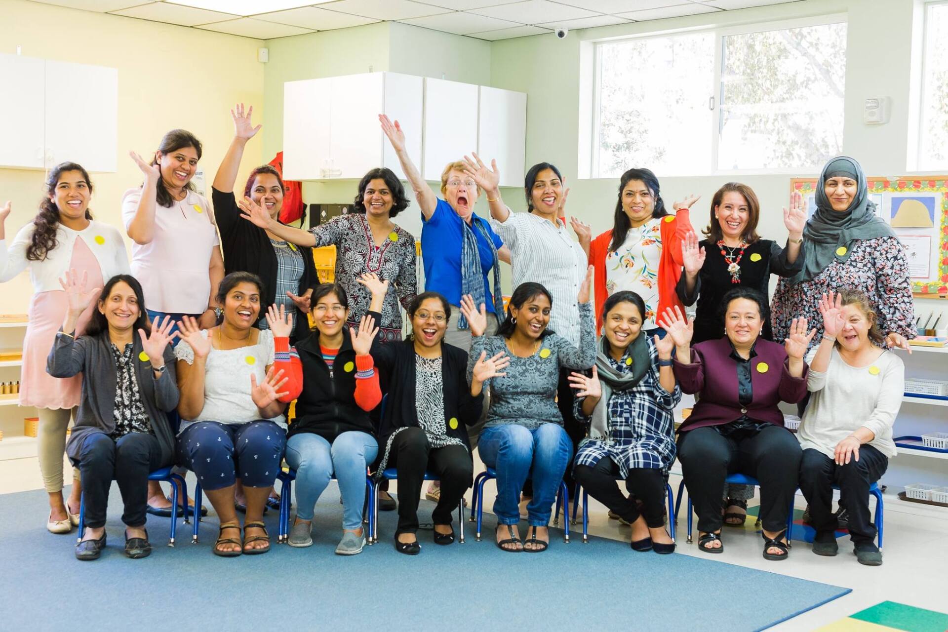 A group of people are posing for a picture in a room with their hands in the air.