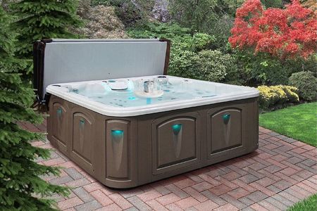 A hot tub is sitting on a brick patio in a garden.