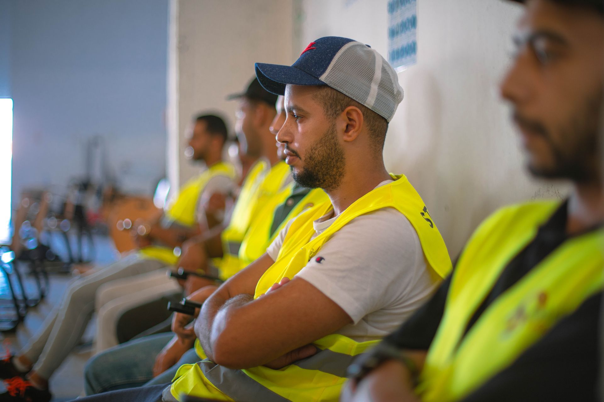 Un groupe d'hommes portant des gilets jaunes et des chapeaux sont assis en rang.
