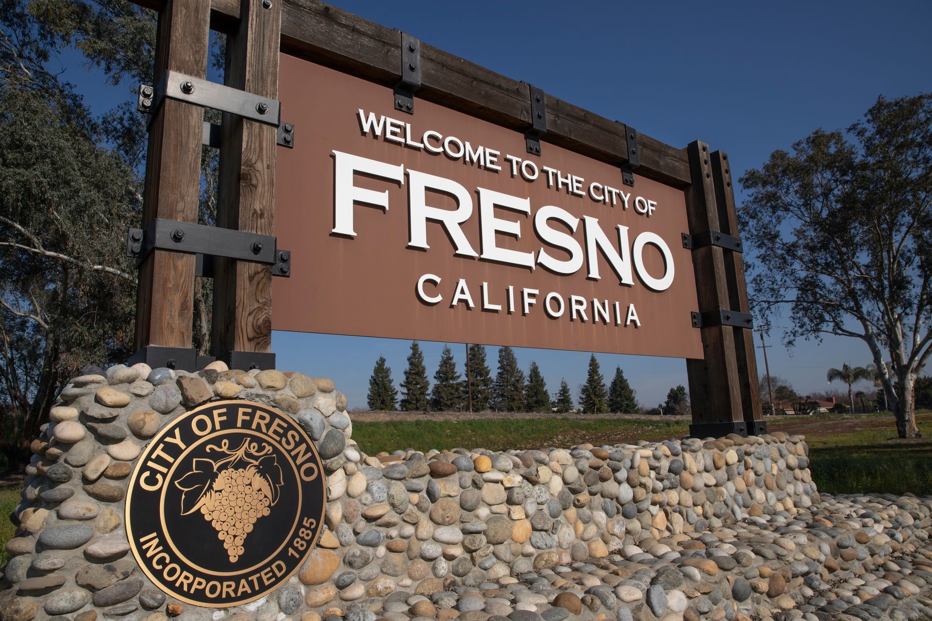 Welcome sign for the city of Fresno, California. Brown sign with white text, mounted on a stone base, sunny outdoors. Welcome sign for the city of Fresno, California. Brown sign with white text, mounted on a stone base, sunny outdoors.