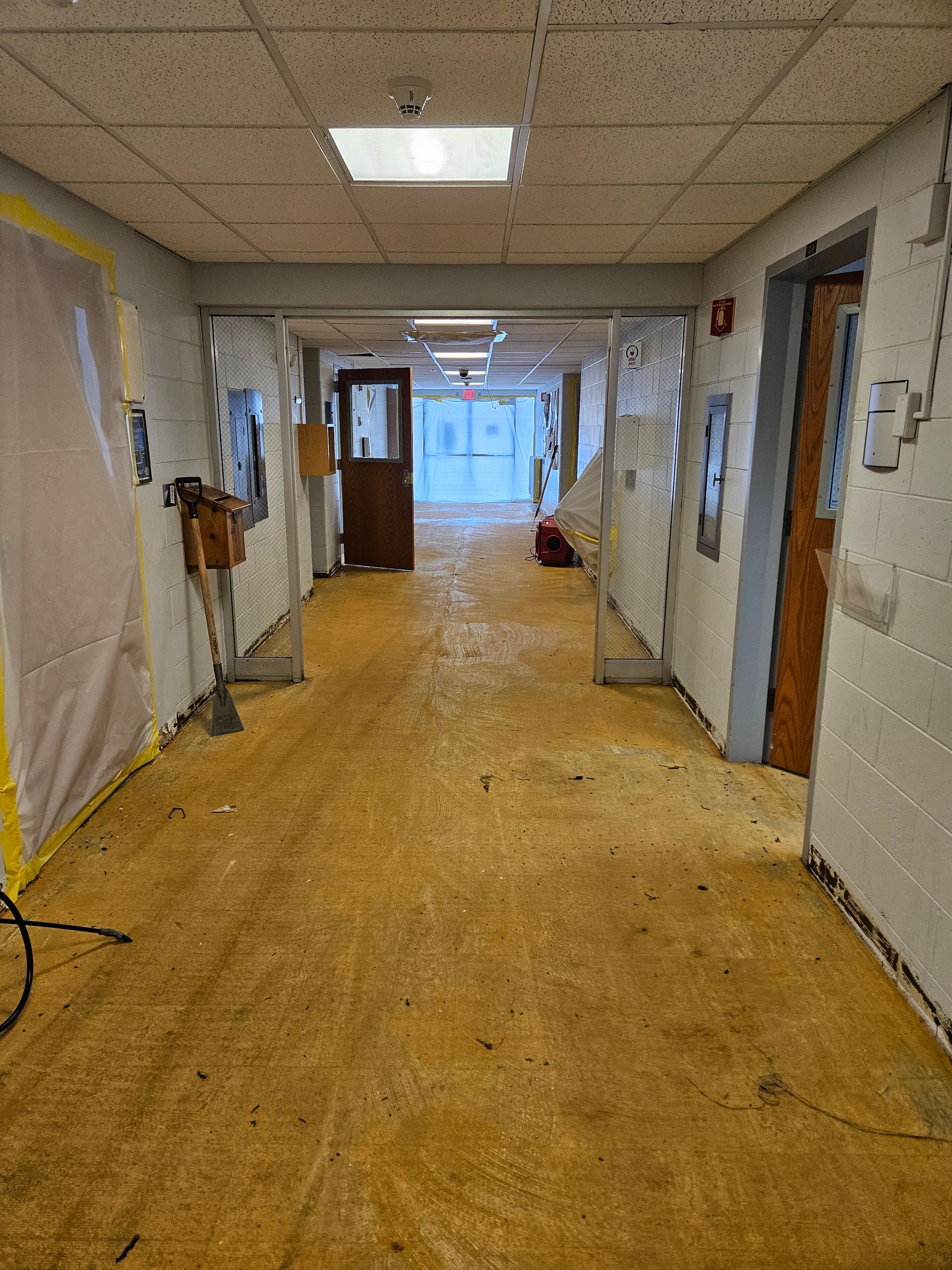 A long hallway with a wooden floor in a building under construction.