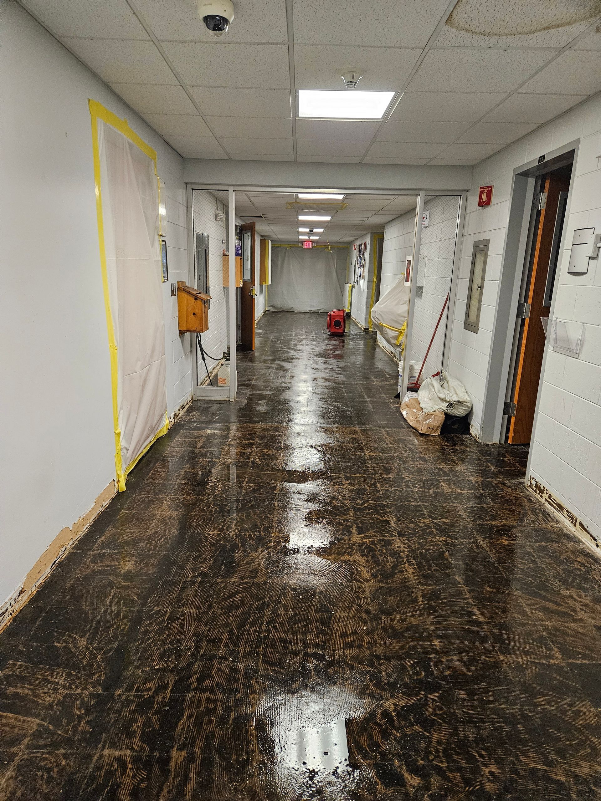 A hallway in a building with a lot of water on the floor.