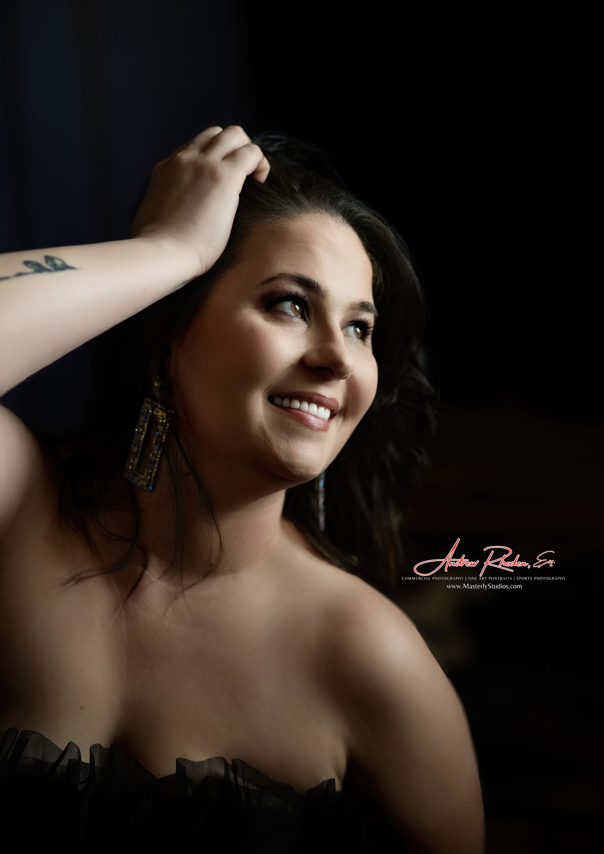 Woman with hand in hair, smiling, dark background.