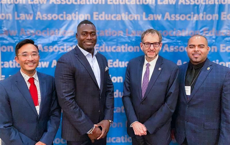 Three people in an office toasting with glasses. Snacks and papers on a table.