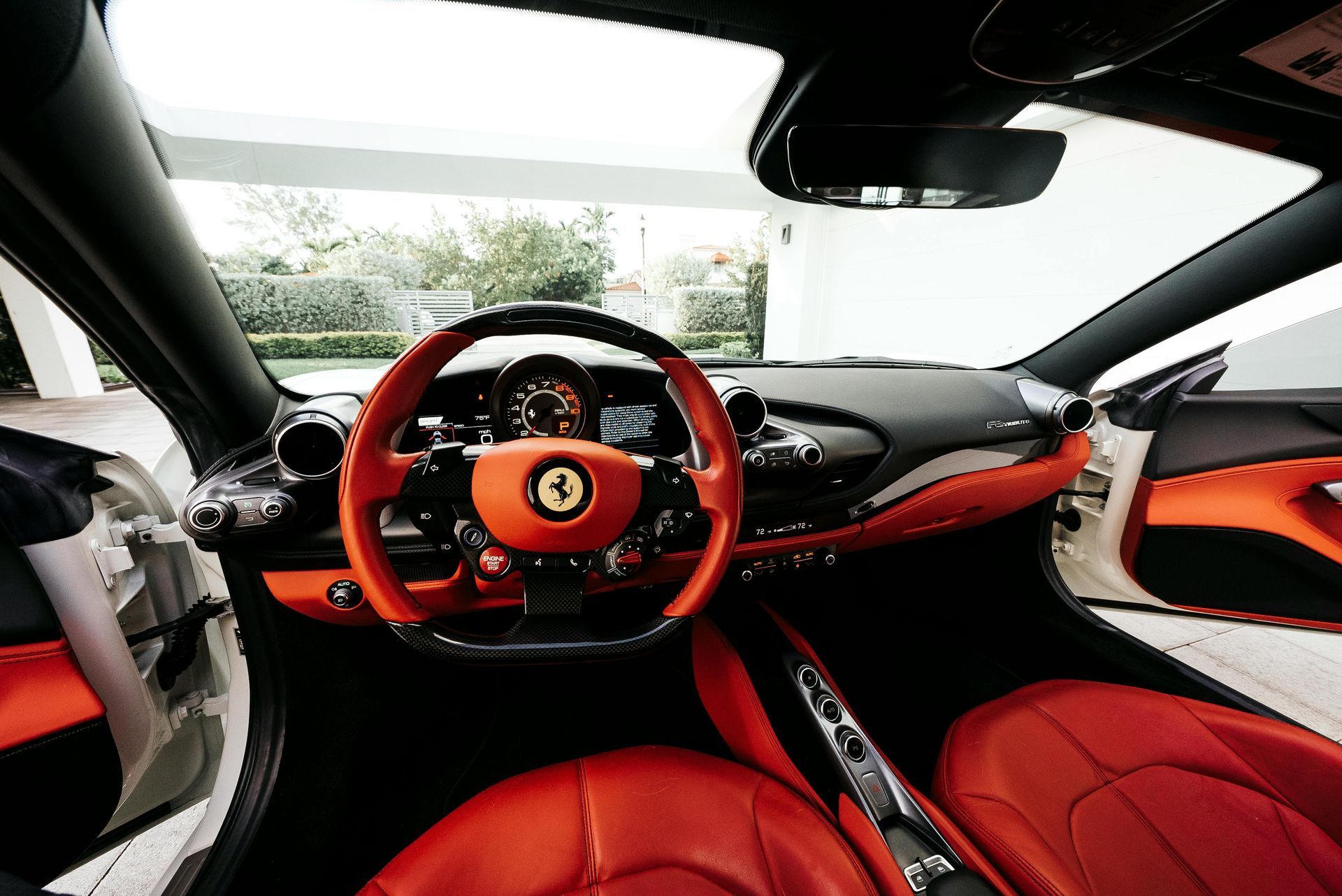 Interior of a Ferrari with red and black leather upholstery, orange dashboard, and steering wheel.