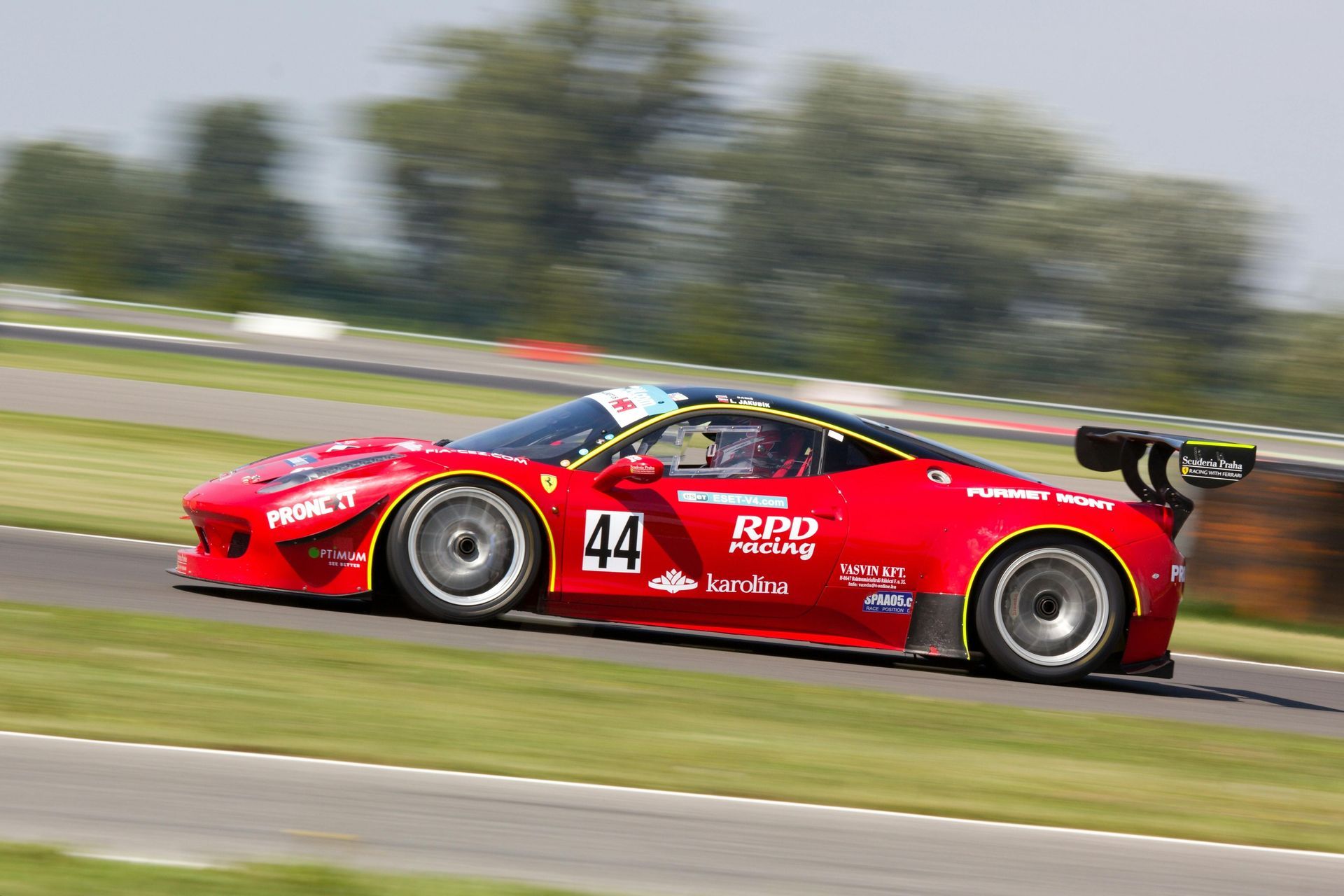 Red Ferrari race car, number 44, speeding around a track.