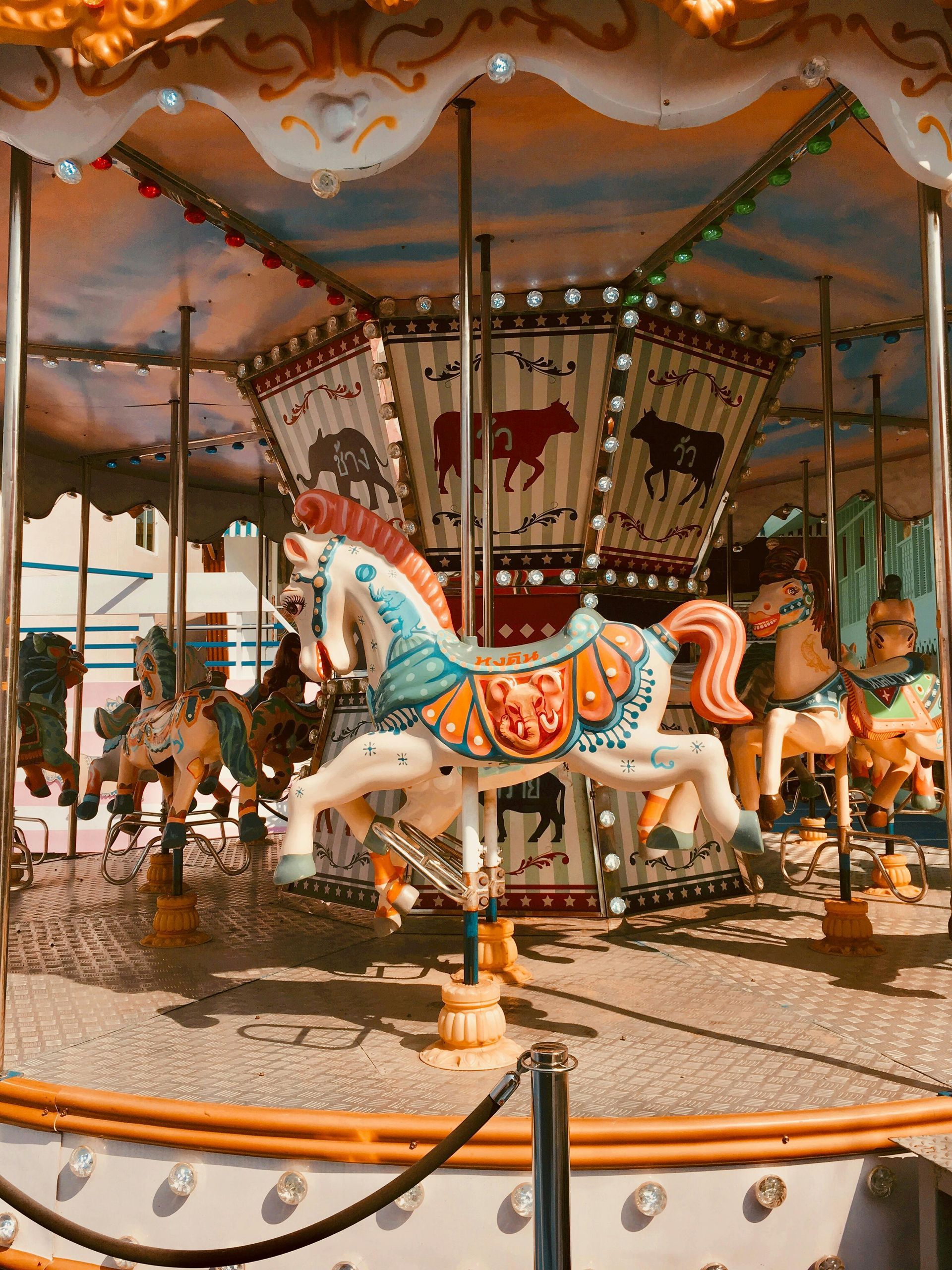 Carousel with white horses, colorful details, spinning at an amusement park.