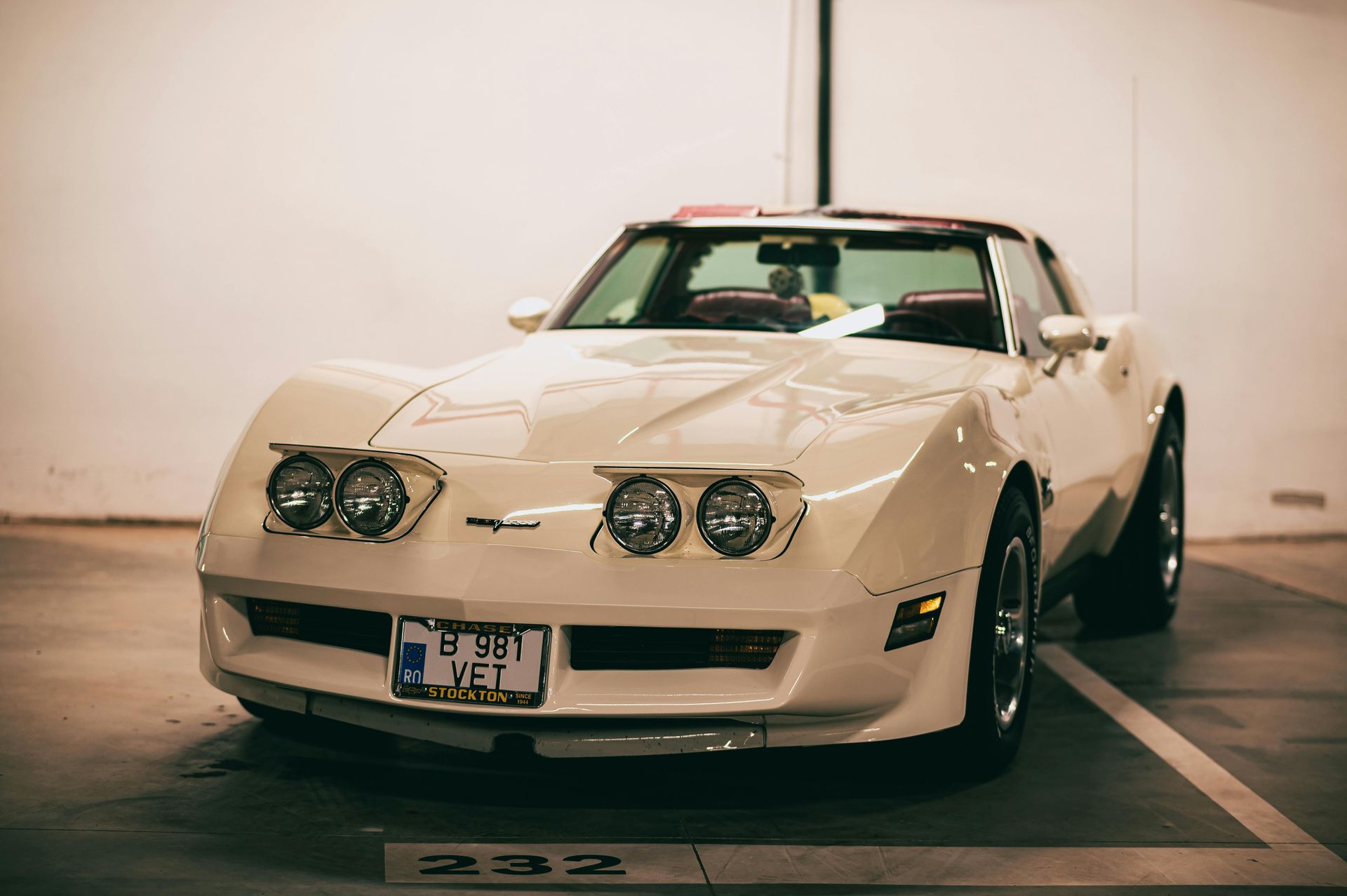 White cosmetic tube, brown cap, angled against a copper-colored rod on a peach background, lit by warm light.