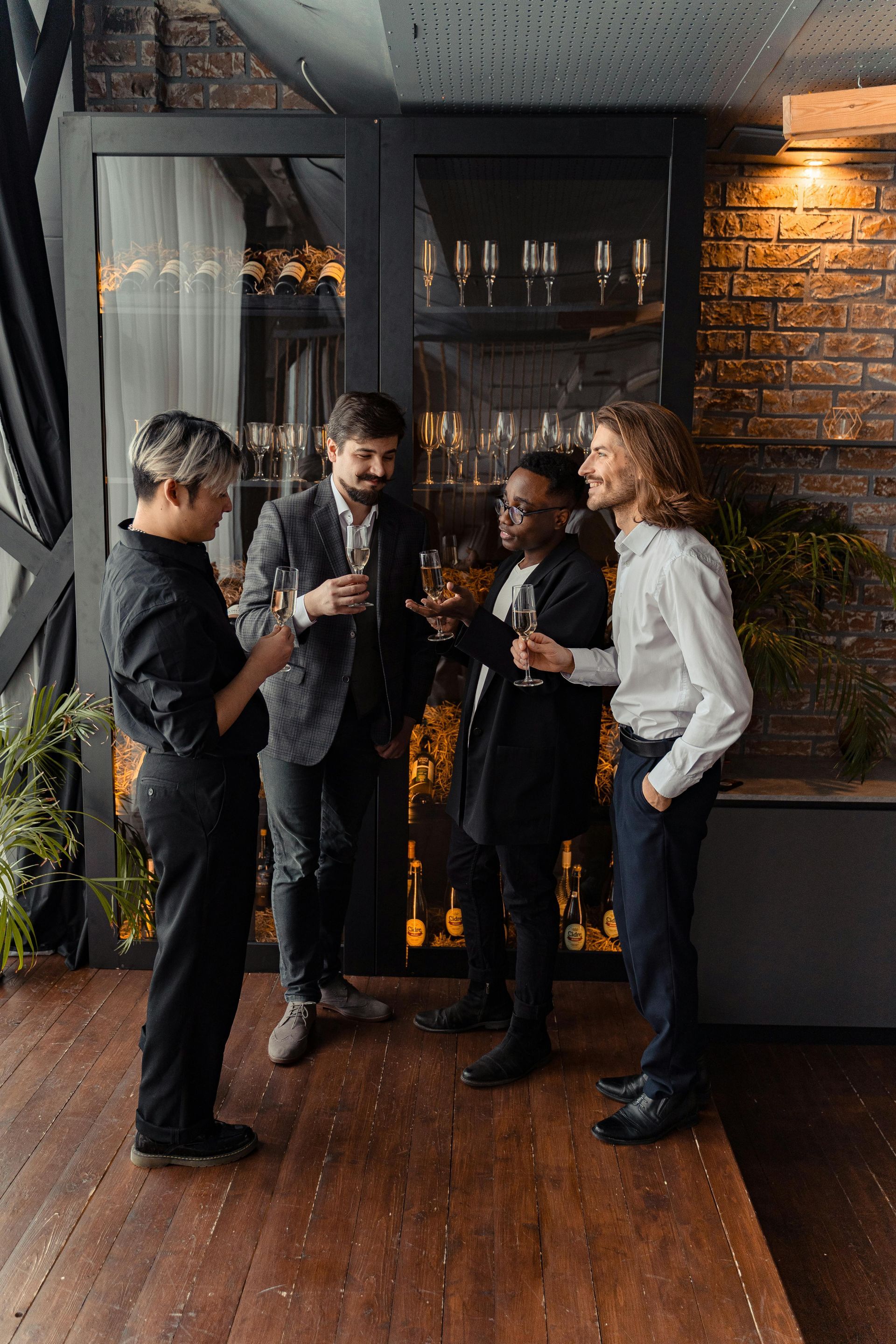 Four people in formal attire with champagne glasses, socializing indoors.