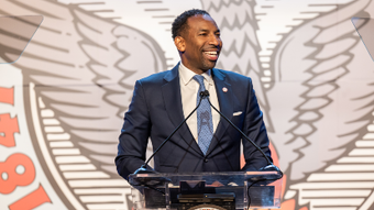 A man in a suit and tie is giving a speech at a podium.