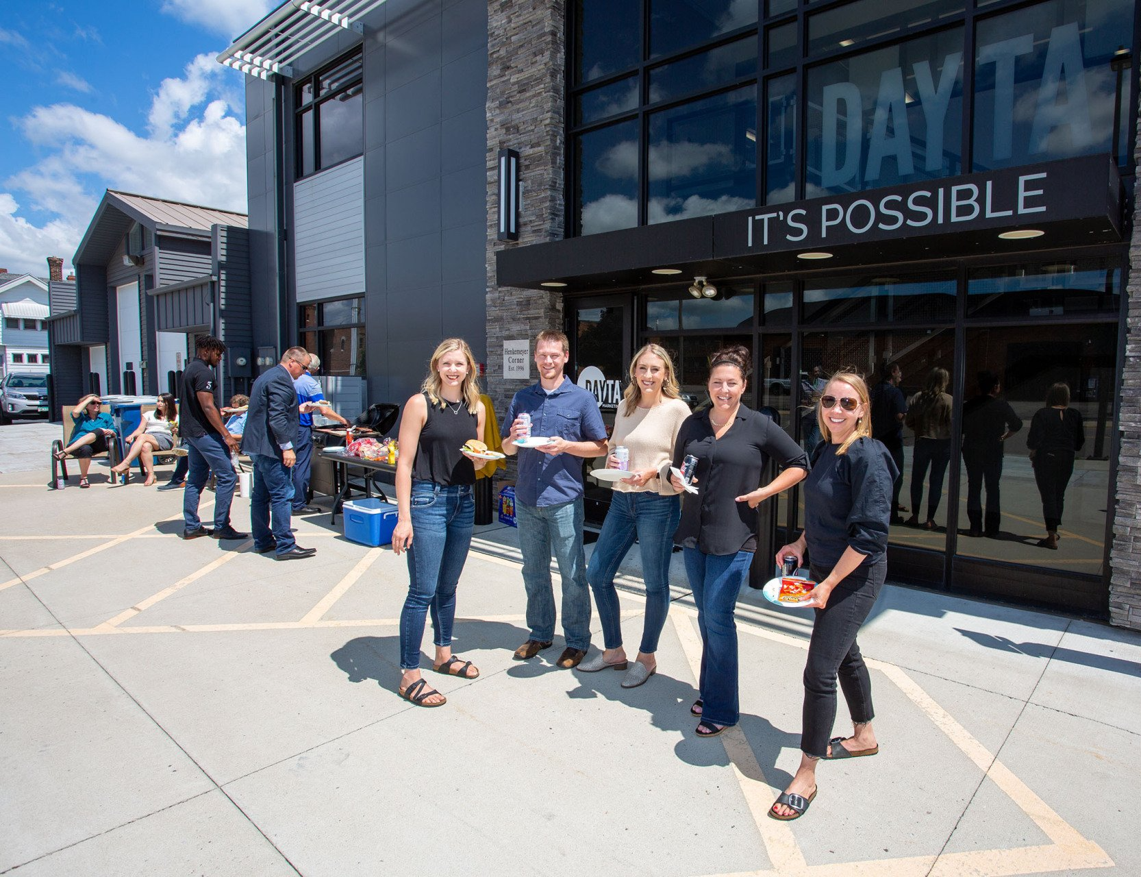 A group of people standing in front of a building that says it 's possible
