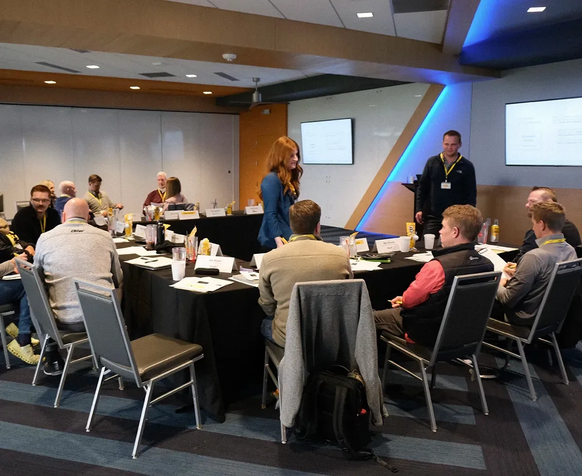 A group of people are sitting at tables in a conference room