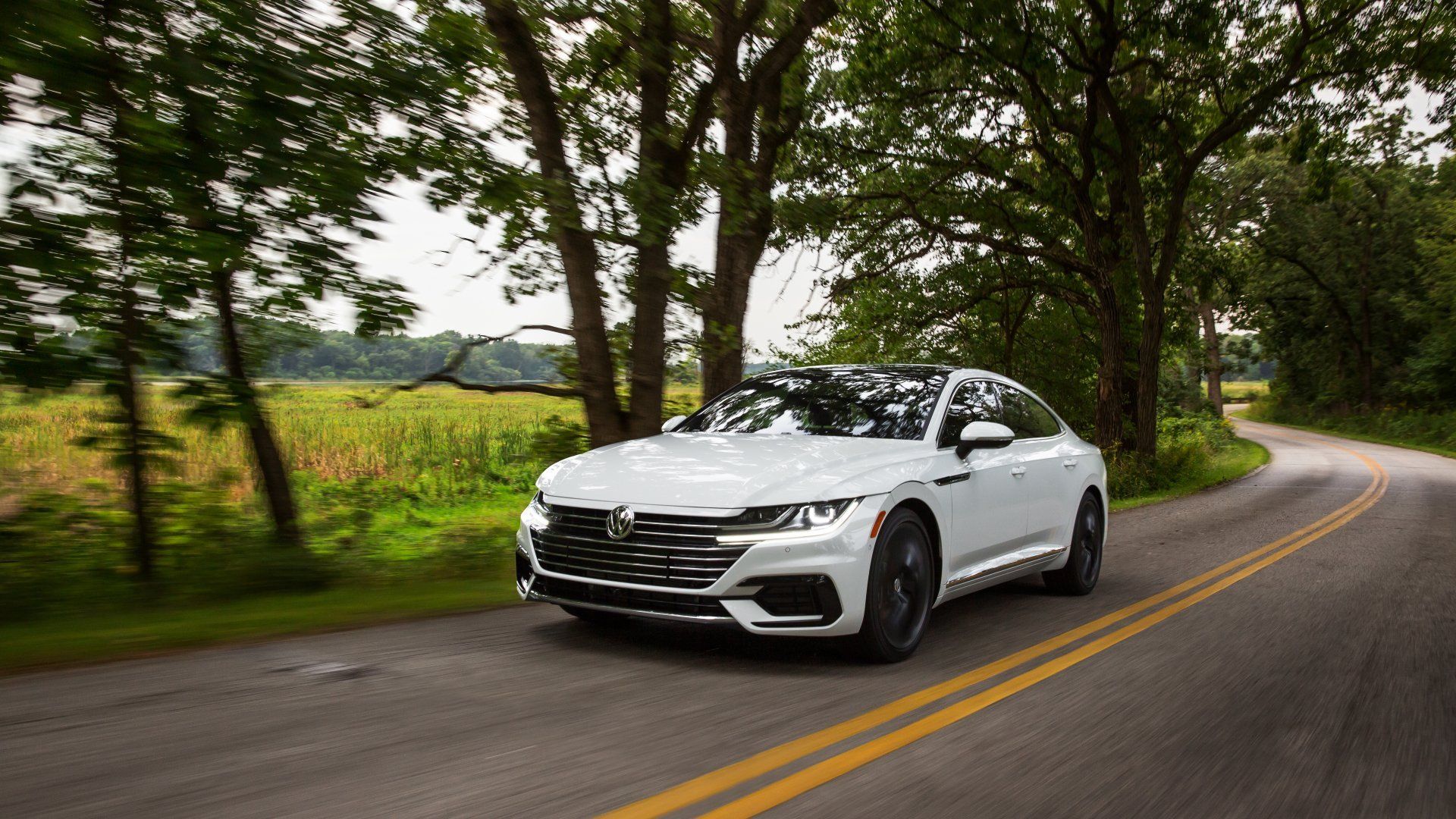 White Mazda car driving on a country road