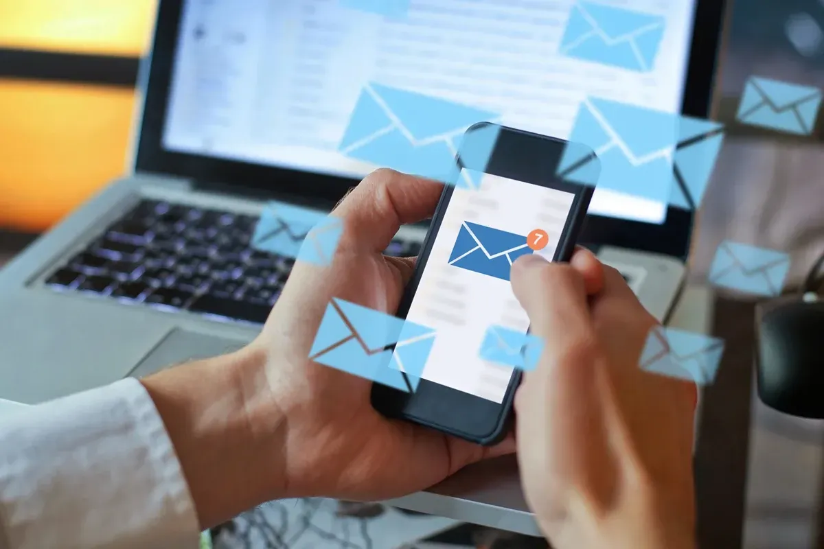 Mechanic with tablet inspecting a car raised on a lift in a workshop.