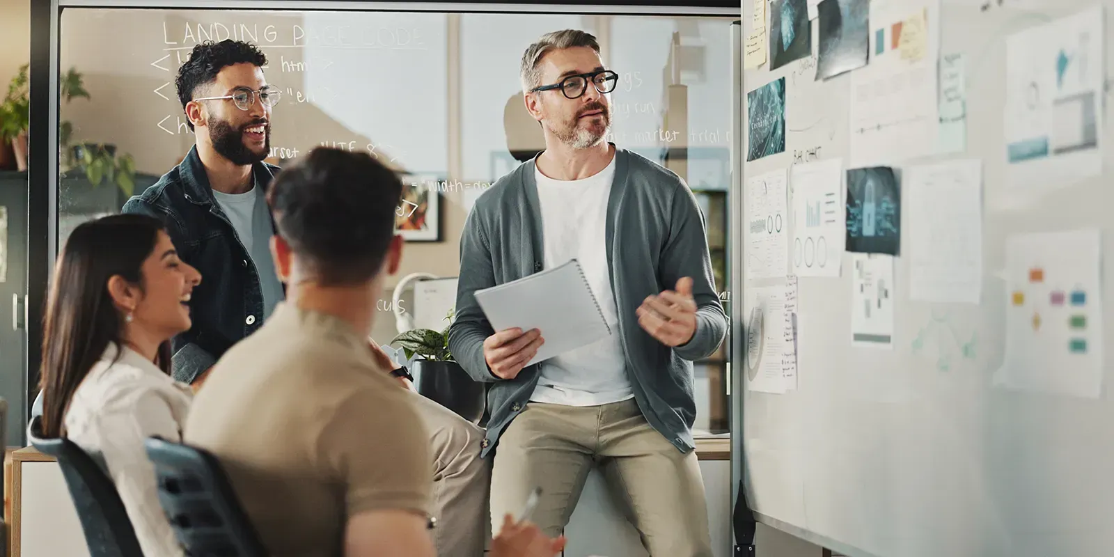 A group of people are having a meeting in front of a whiteboard.