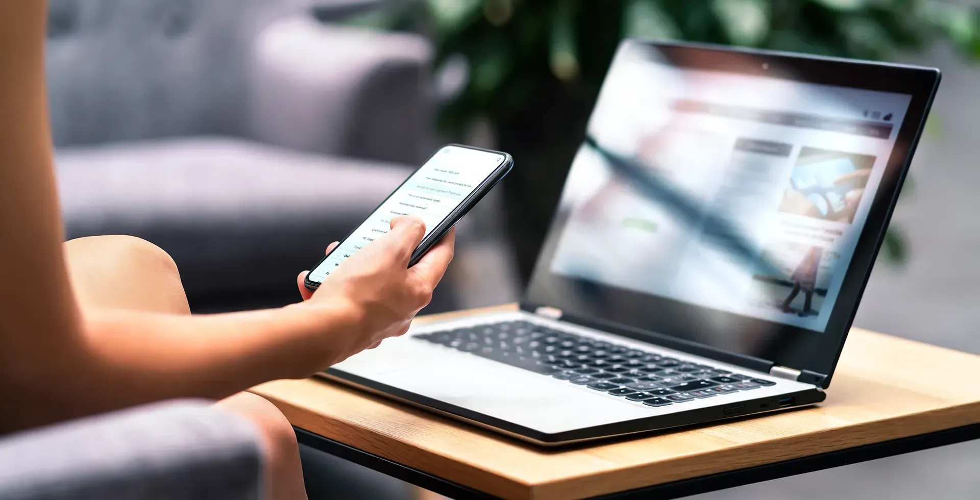 Lady holding phone with laptop sitting on desk