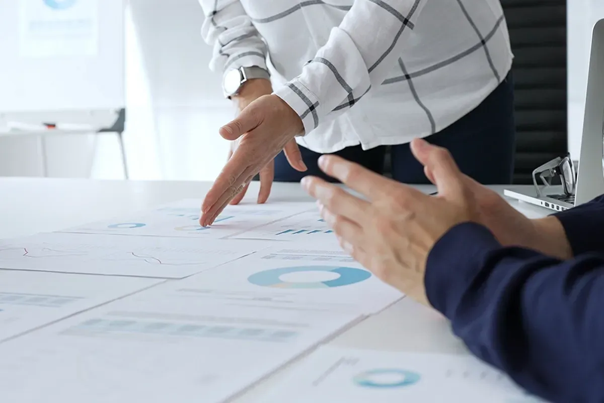 Mechanic with tablet inspecting a car raised on a lift in a workshop.